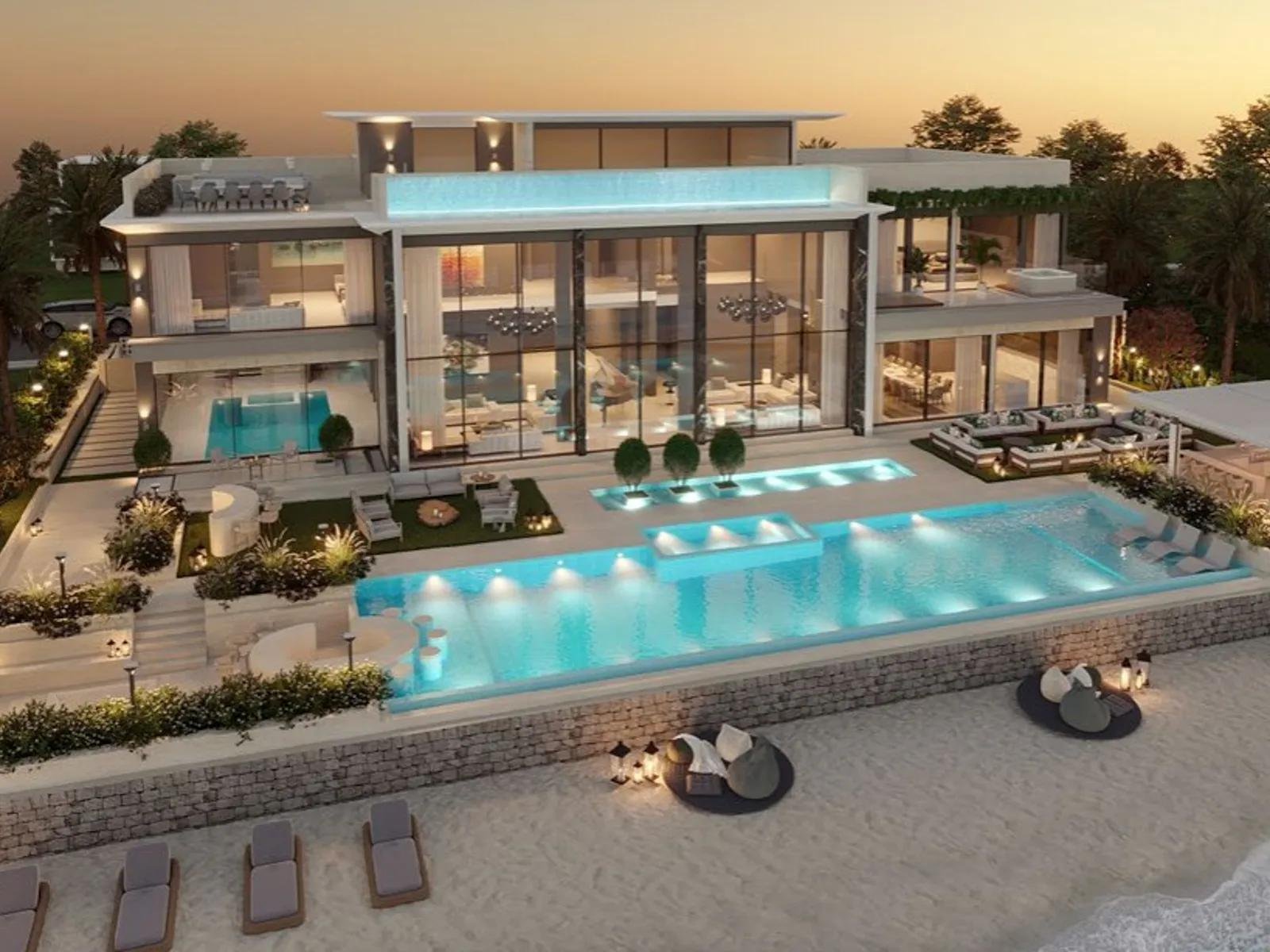 Beachfront villa with an illuminated pool at dusk